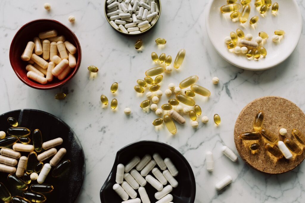Assorted supplement capsules and pills arranged in bowls on a marble surface representing gut health supplement choices