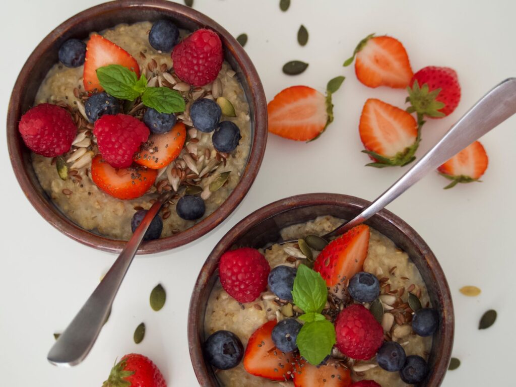 Oatmeal breakfast bowls topped with fresh strawberries, raspberries, blueberries, and seeds for a high-fiber gut health breakfast