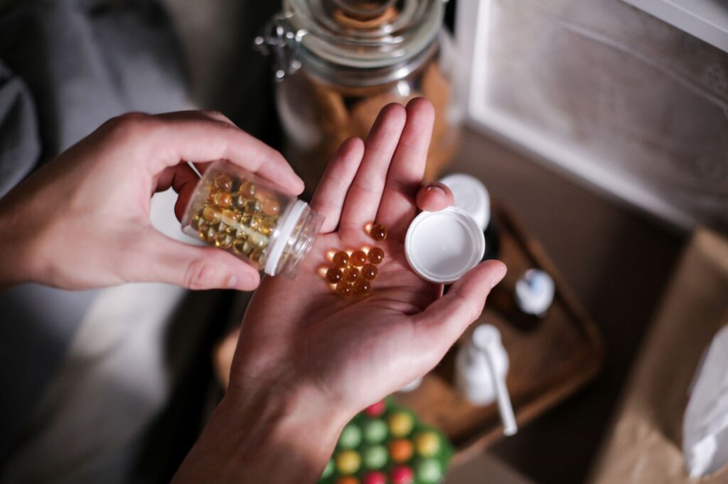 Hands holding digestive enzyme supplement capsules poured from a small glass bottle