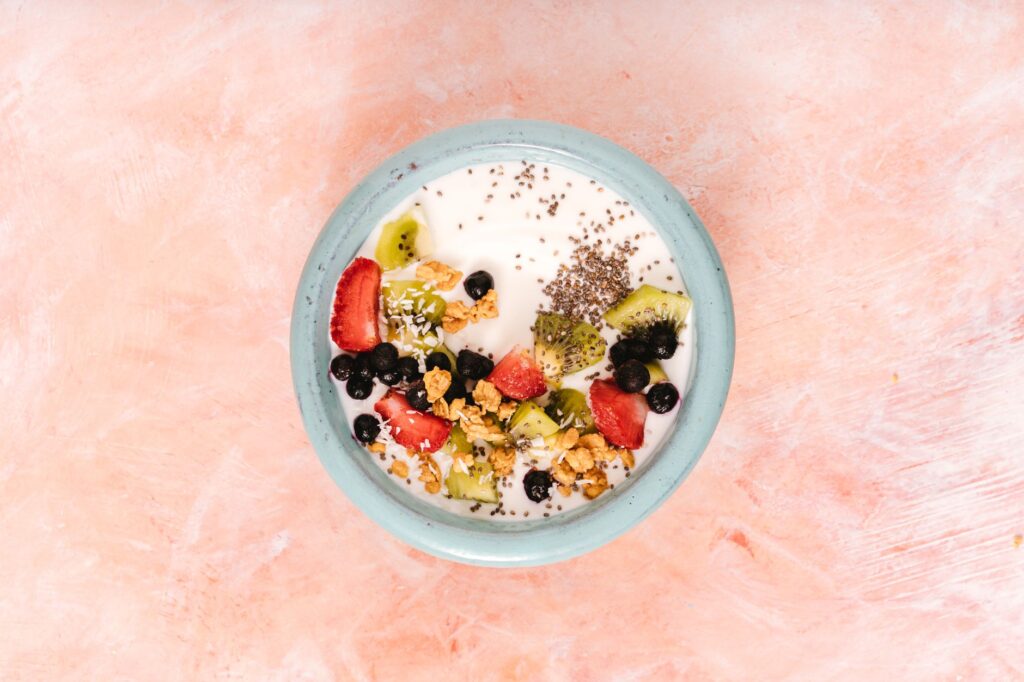Overhead view of a yogurt bowl topped with strawberries, kiwi, blueberries, granola, and chia seeds — a probiotic and prebiotic-rich gut health meal