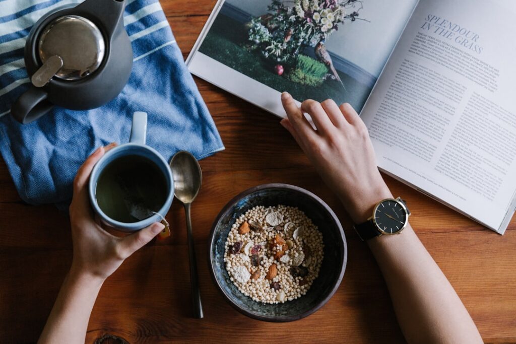 Person enjoying a relaxed morning routine with oats and green tea at a wooden table