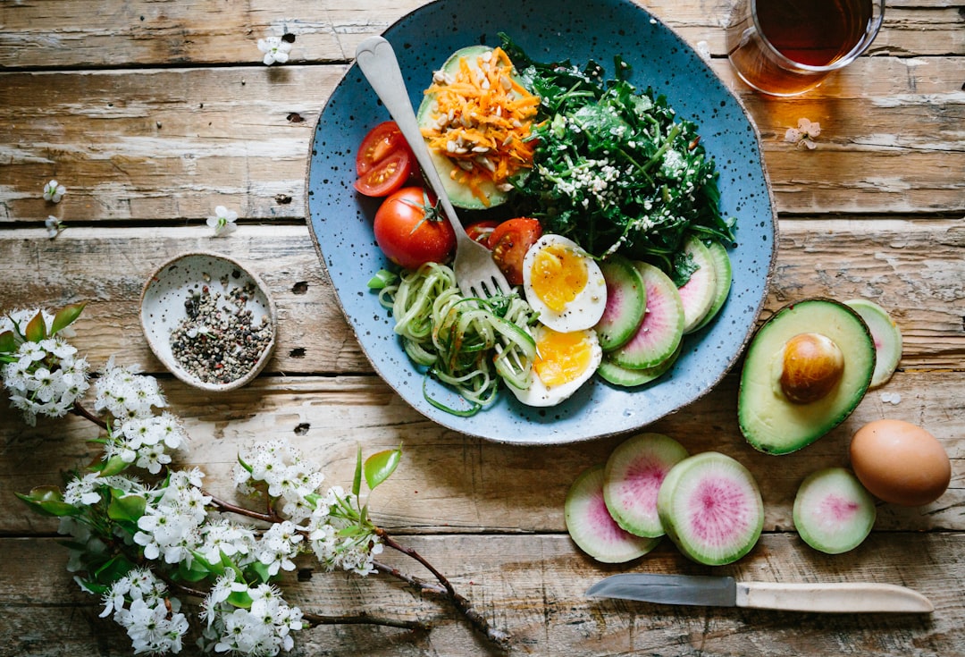 Healthy IBS-friendly meal with boiled egg, fresh vegetables, avocado and greens on a wooden table — Photo by Brooke Lark on Unsplash