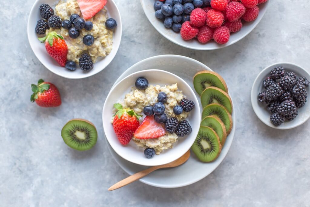 Bowls of oatmeal topped with fresh berries, strawberries, and kiwi — fiber-rich gut-friendly foods