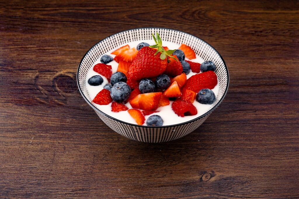 A bowl of plain yogurt topped with fresh strawberries and blueberries — a probiotic-rich gut health food