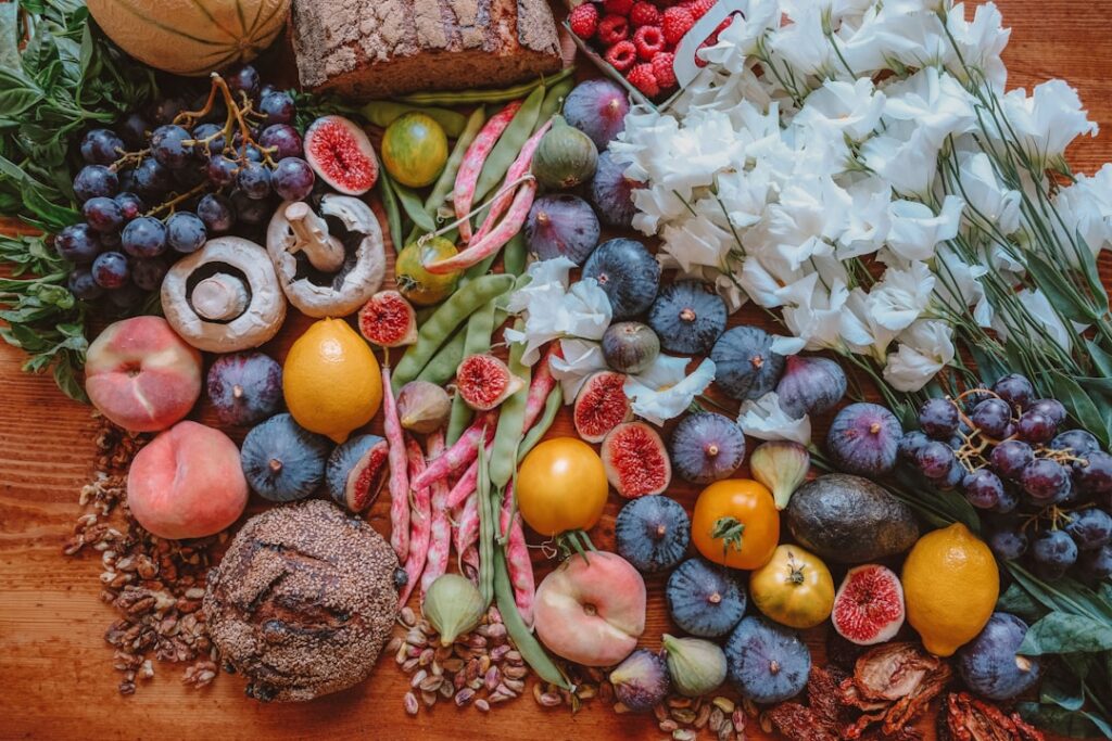 A colorful spread of fiber-rich fruits, figs, grapes, beans, and whole foods representing prebiotic fiber sources that support beneficial gut bacteria.