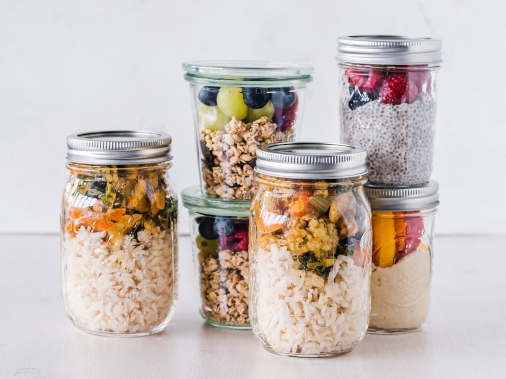 Healthy meal prep jars filled with grains, oats, berries and vegetables ready for the week ahead.