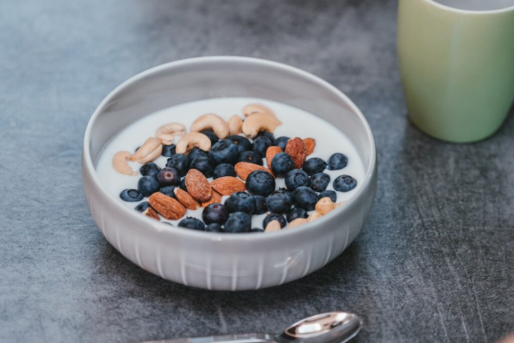Bowl of yogurt with blueberries, almonds and nuts representing gut-friendly foods to reduce bloating naturally