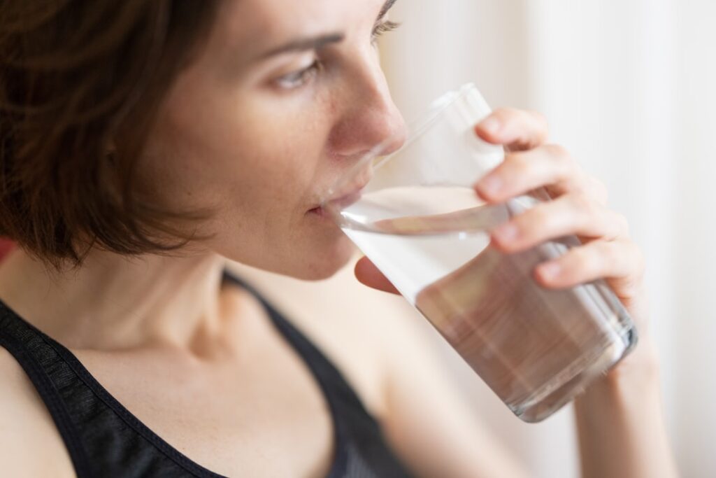 Woman drinking a glass of water to support healthy digestion and gut hydration