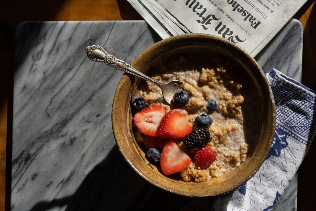 Warm oat breakfast bowl topped with strawberries and blueberries — a simple, gut-friendly way to start the day.